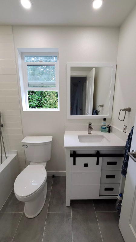 A picture of a tan wall mounted cabinet with a single hole faucet and wooden tile floors. 